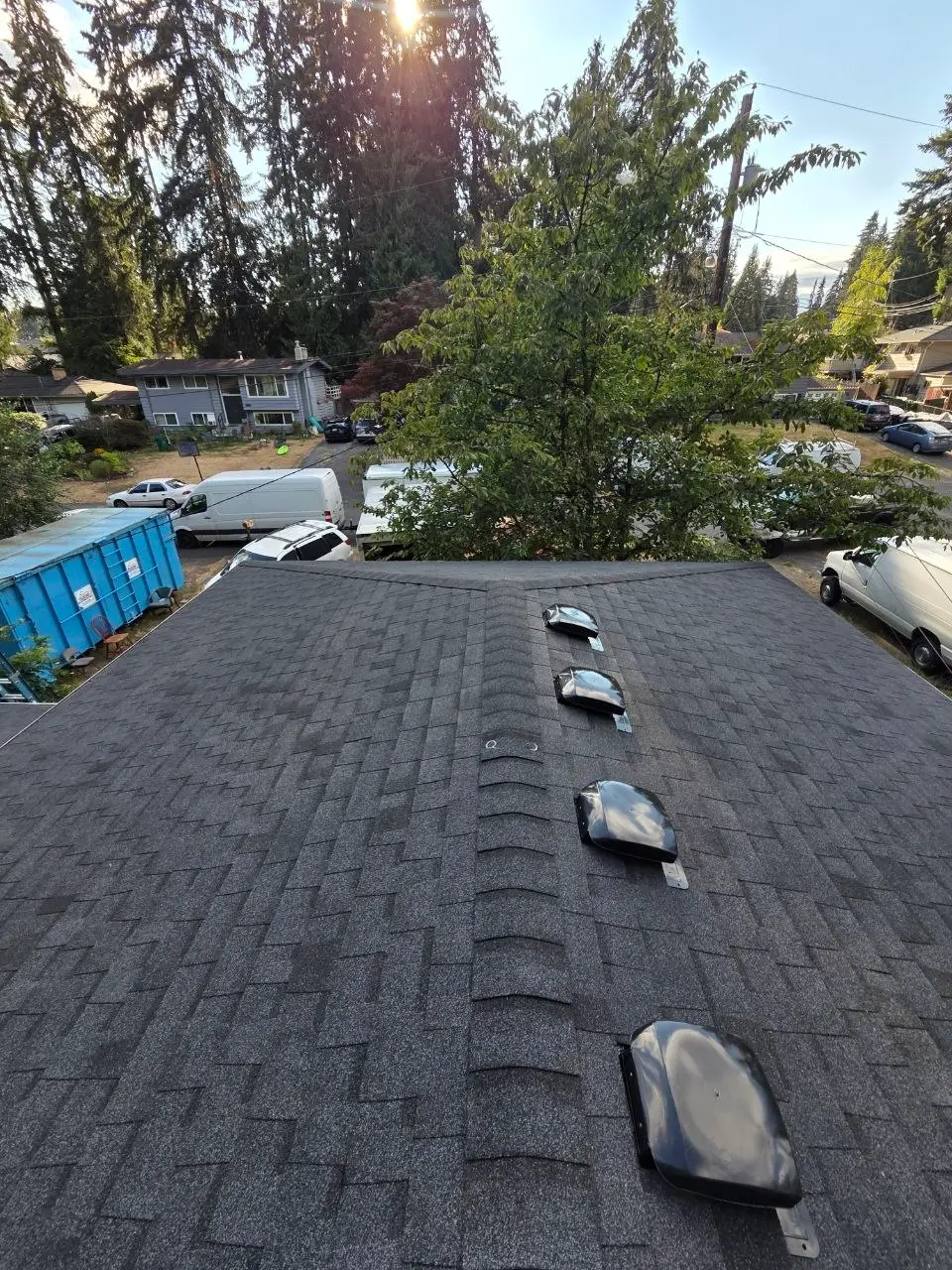 New charcoal shingle roof ridge vents with dumpster