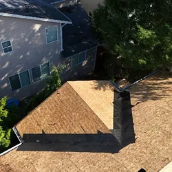 Aerial tear-off showing exposed plywood deck before shingle roof replacement