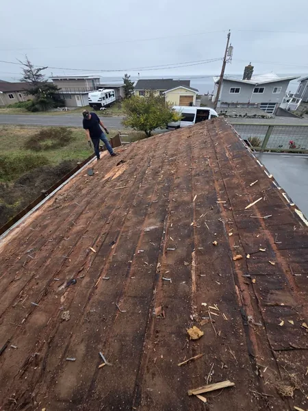 Crew member on a stripped roof deck during tear-off
