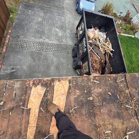 Tear-off debris loaded in a dumpster beside an open deck