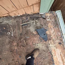 Rotted roof deck and torn underlayment at a wall