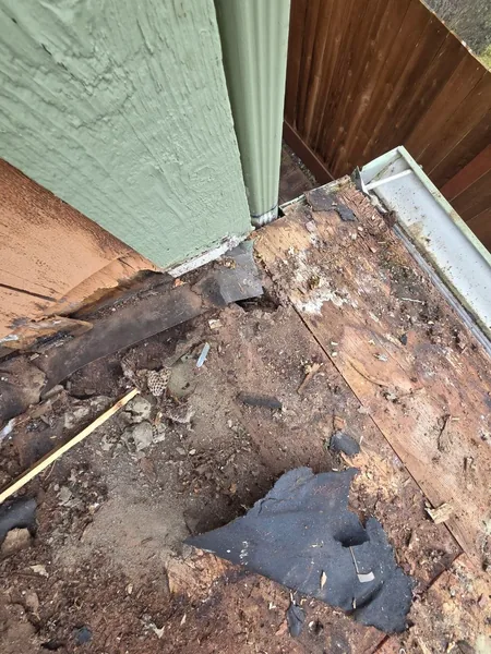 Rotted roof deck at a wall corner and downspout